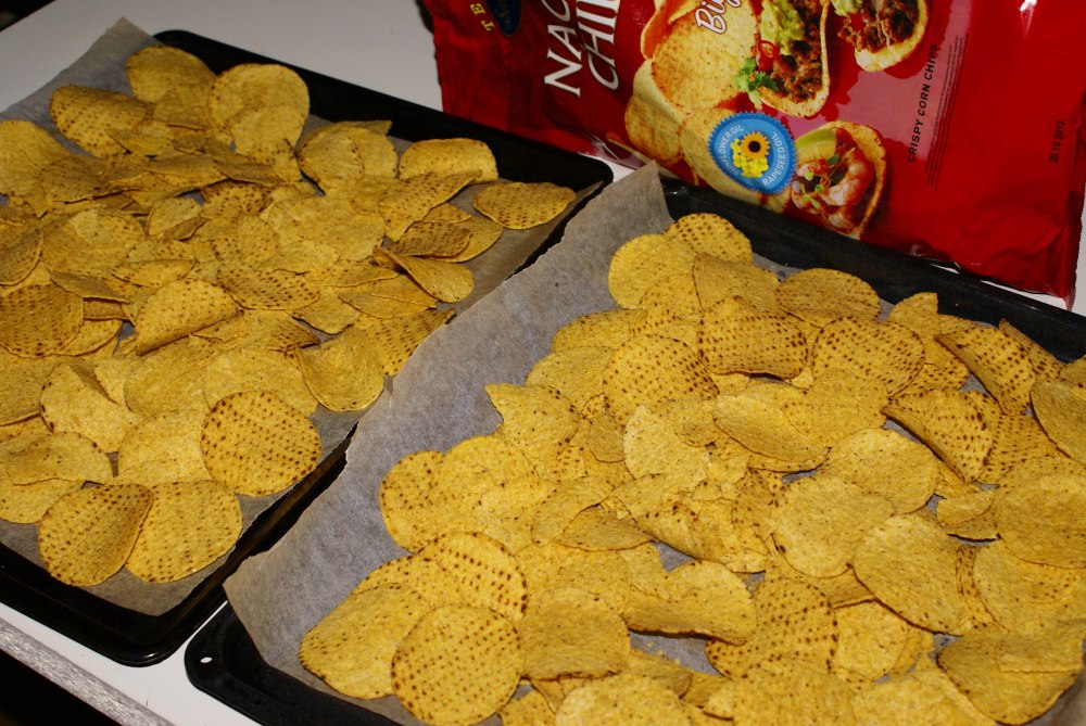Legg et lag nachos utover bakepapirkledt stekebrett.