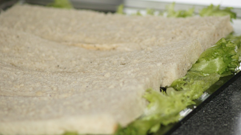 Bruk et stor serveringsfat til å lage terten på og start med å legge salatblader på brettet, deretter legges underdelen av loffene oppå, tett i tett.
